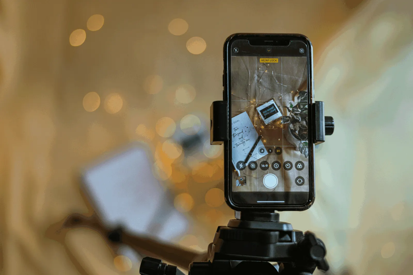 A phone on a tripod recording, with blurred lights in the background.