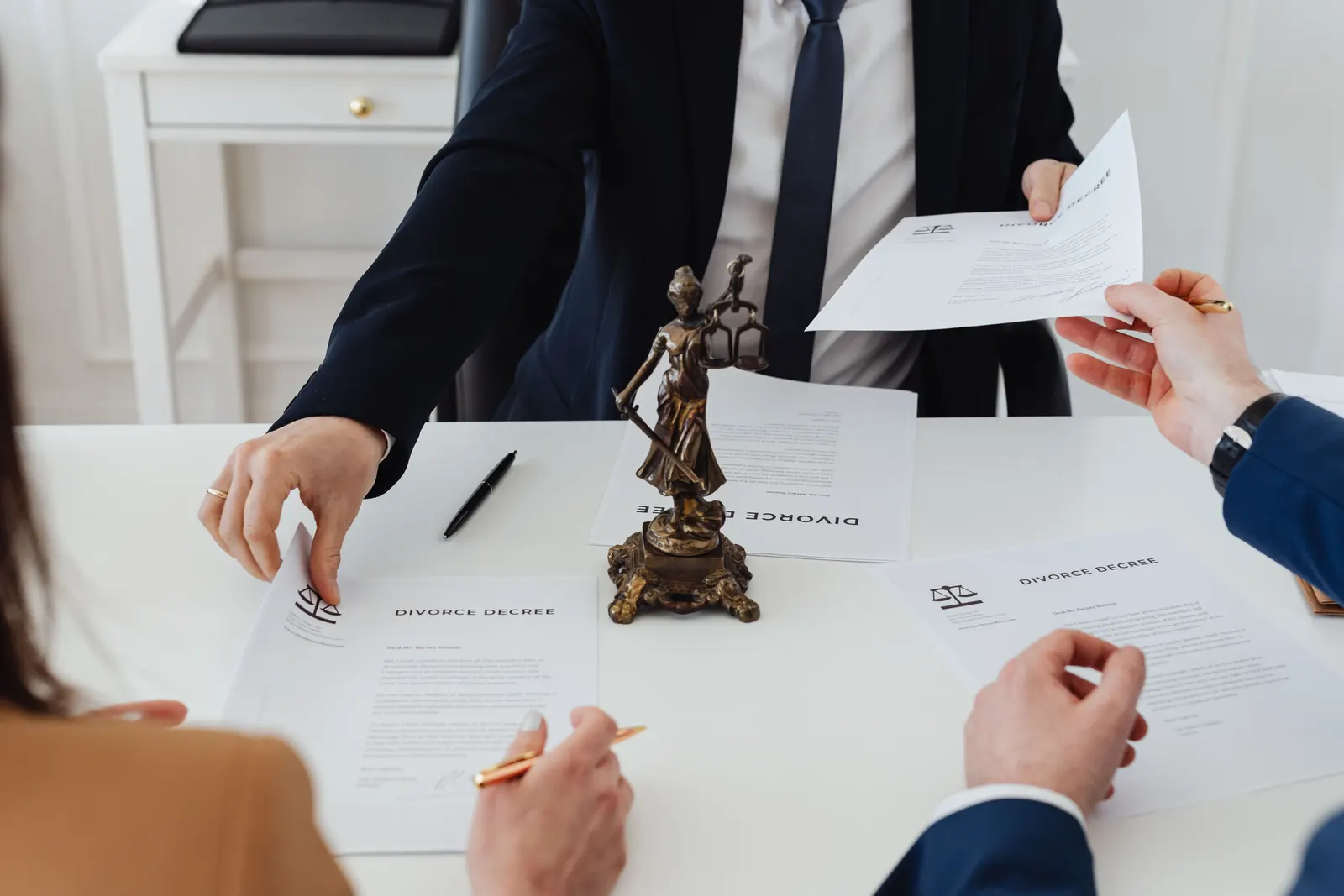 Documents on an office desk, with a statuette of Lady Justice in the middle.