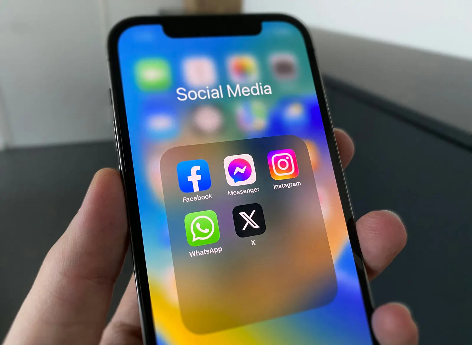 A phone with a folder of social media apps open on the screen.